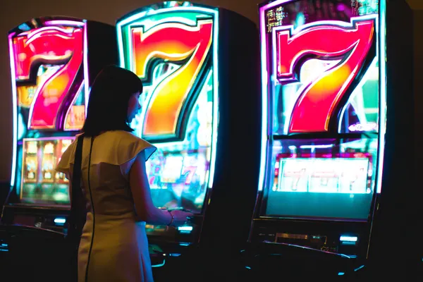 A woman smiling while playing online games on her laptop, surrounded by neon casino elements, showcasing KKBDD’s diverse game collection.